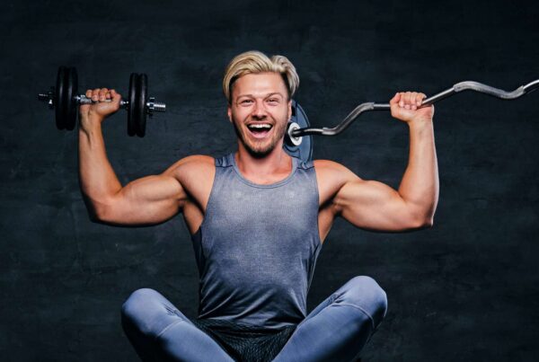 un felice atleta bodybuilding con manubrio e bilanciere dopo un pesante allenamento