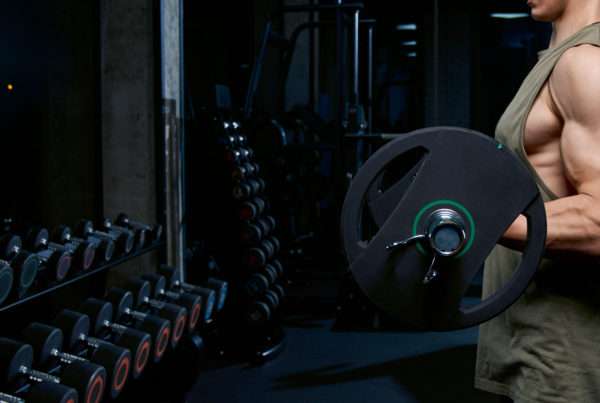 Un uomo muscoloso si allena con un bilanciere davanti allo specchio