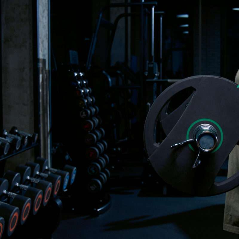 Un uomo muscoloso si allena con un bilanciere davanti allo specchio